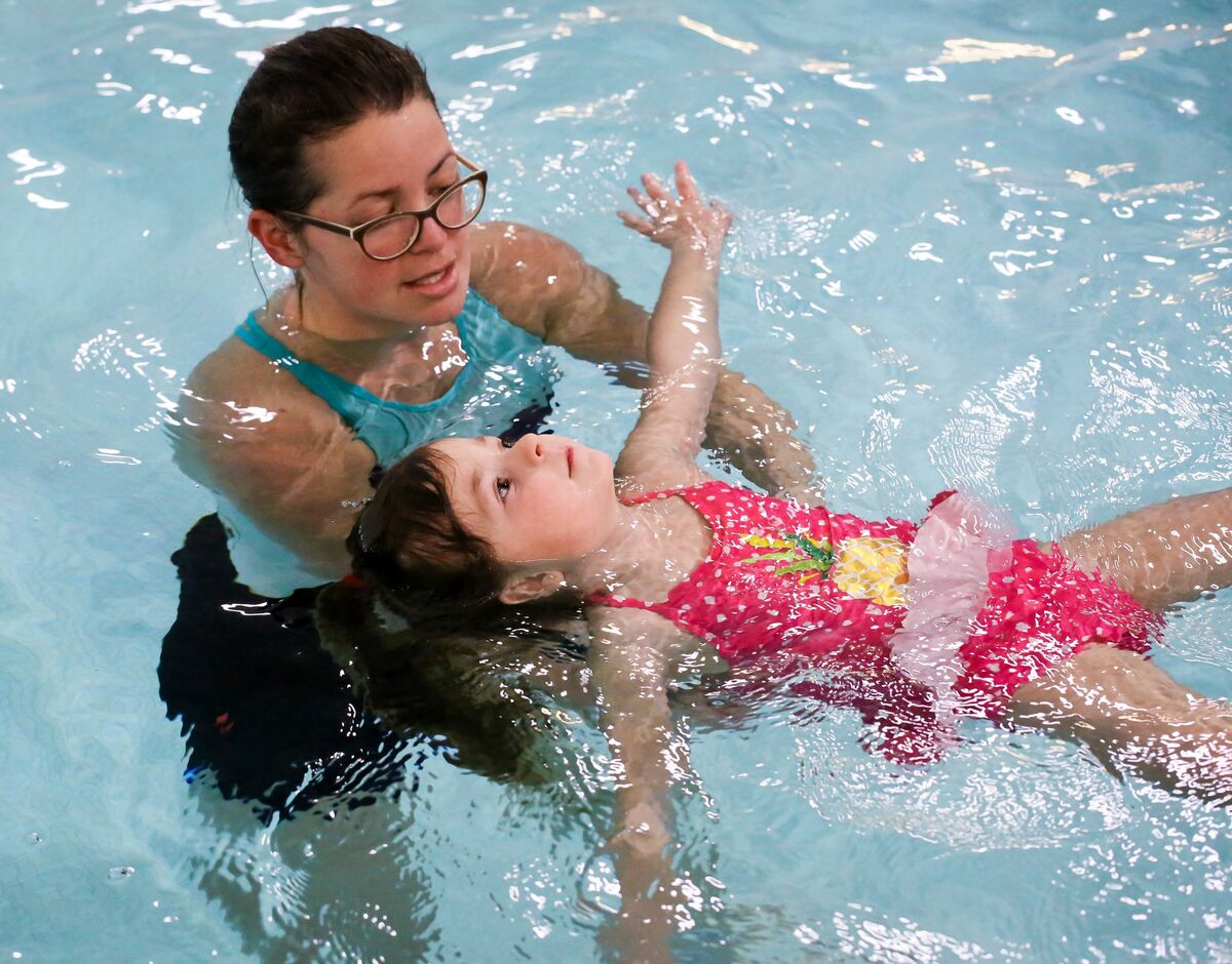 woman teaching girl to swim
